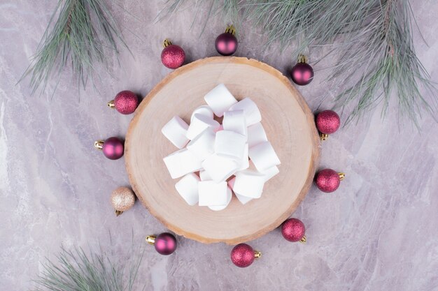 Gustosi marshmallow su una tavola di legno con palline di quercia intorno