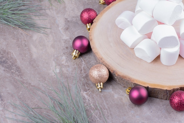 Foto gratuita gustosi marshmallow su una tavola di legno con palline di quercia intorno