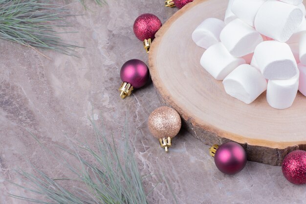 Yummy marshmallows on a wooden board with oak tree balls around