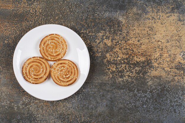 Yummy sesame seeds biscuits on white plate.