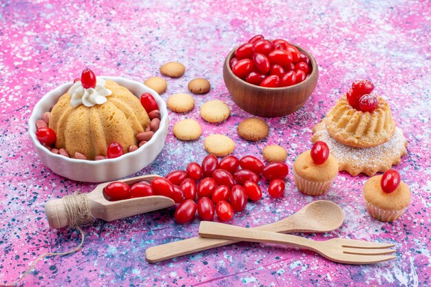 вкусный простой торт со сливками и свежим арахисом, печенье из красного кизила на ярко-фиолетовом столе, бисквитный торт, сладкий орех и ягода
