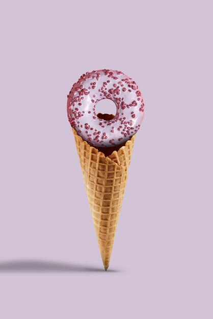 Yummy sprinkled and glazed donut in sweet wafer cone against lilac background. Concept of food, treats and unhealthy nutrition. Close up, copy space