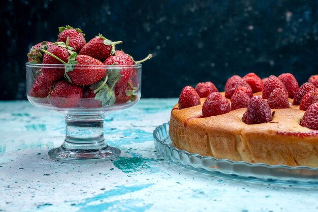 밝은 파란색 책상에 신선한 빨간 딸기와 함께 과일 모양의 맛있는 딸기 케이크 라운드