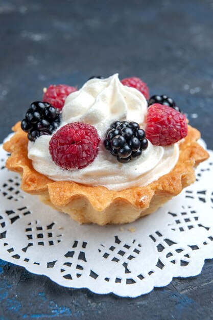 yummy sweet cake with berries and cream on dark-grey