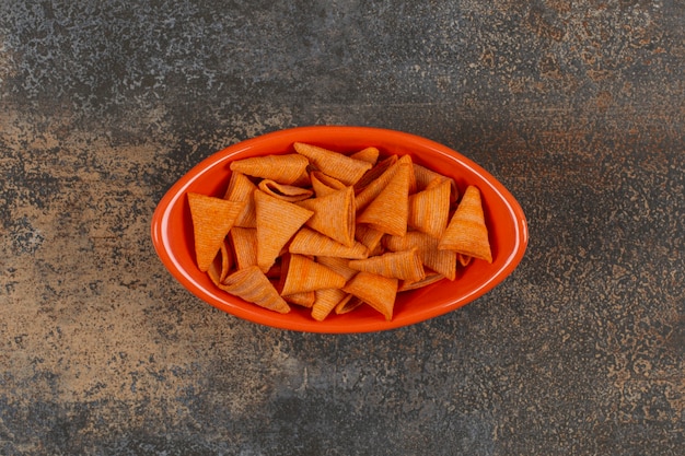 Вкусные чипсы треугольника в оранжевой миске.