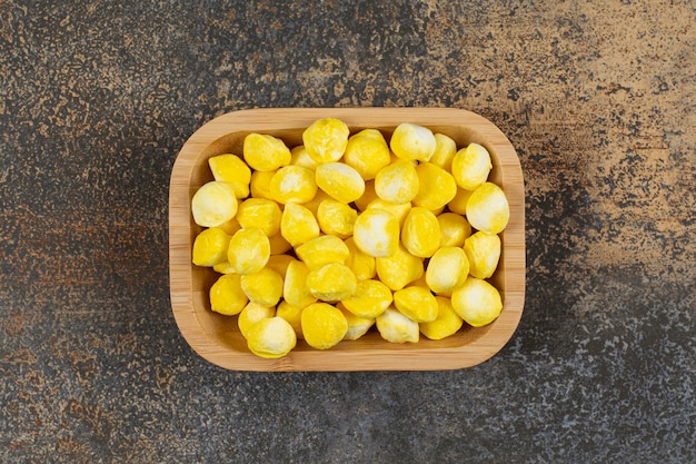 Yummy yellow candies on wooden plate. 