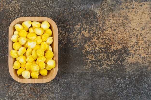 Yummy yellow candies on wooden plate. 