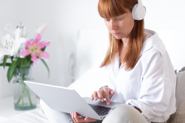 Free photo yyoung girl listens to music and works at the computer flower lily indoor