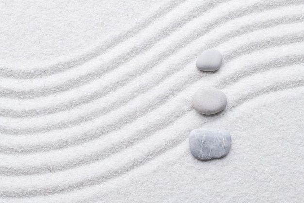 Zen stones white sand background in art of balance concept