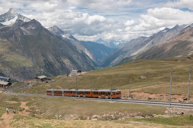 체르마트, 스위스 - 2017년 6월 24일: 관광객을 태운 고르너그라트 기차가 스위스, 스위스, 유럽 국립공원의 마터호른 산으로 갈 것입니다. 여름 풍경 anddramatic 푸른 하늘
