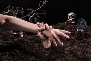 Foto gratuita persona di cattura della mano dello zombie al cimitero di halloween