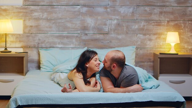 Zoom in shot of cheerful couple wearing pajamas. Smiling wife.