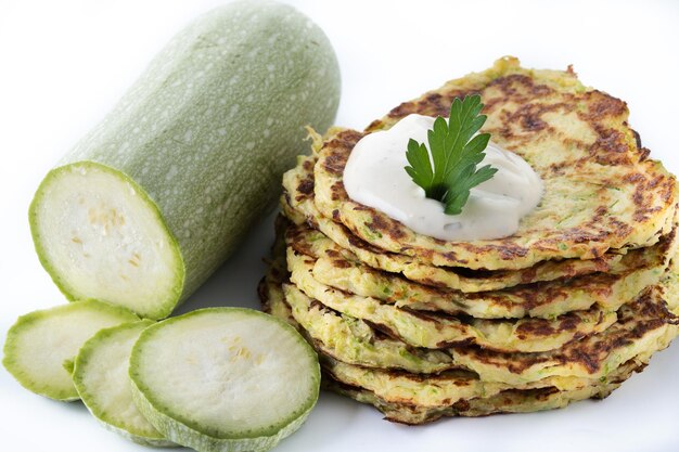 Zucchini fritters with yogurt sauce on wooden table
