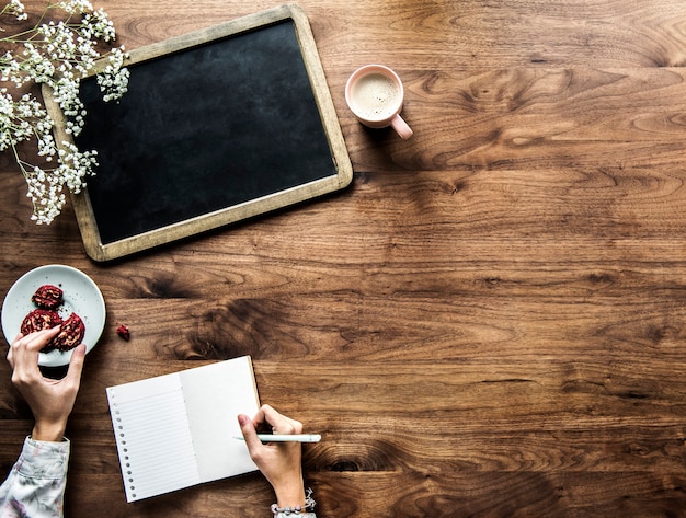 Aerial view of empty black board and woman writing on an empty journal with copy space