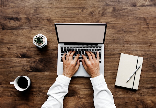 Aerial view of a man using computer laptop on wooden table