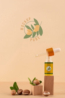 Mock-up di bottiglia cosmetica all'olio di argan con podio a forma di legno e noccioli