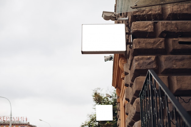 A billboard, mockup, from the side of an building outside against a beautiful blue sky