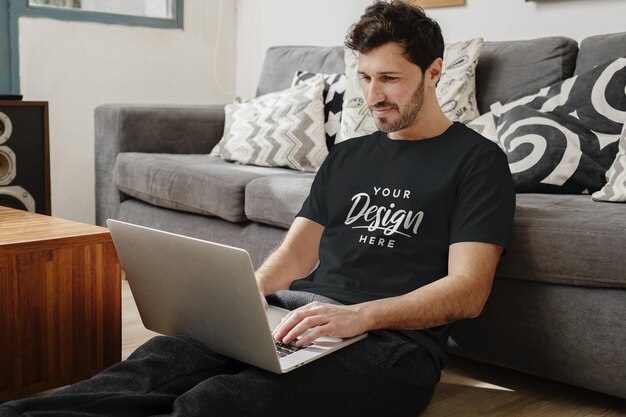 Black tshirt mockup man in living room with laptop