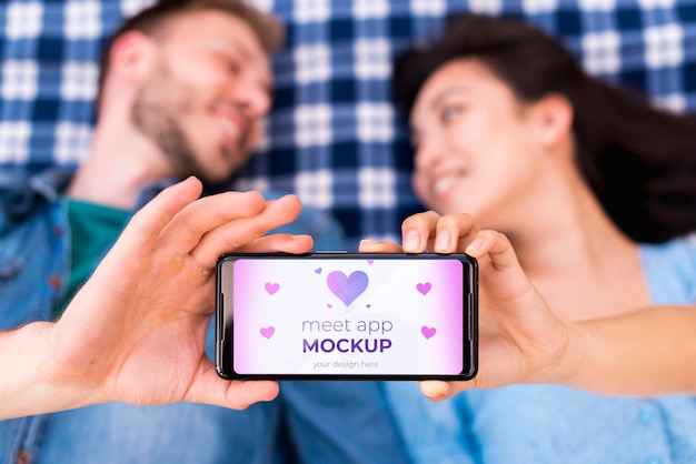 Blurred people holding meet app mock-up on mobile phone