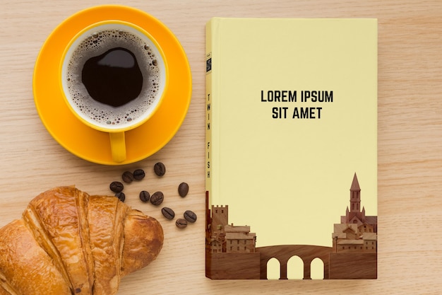 Book cover composition on wooden background with cup of coffee