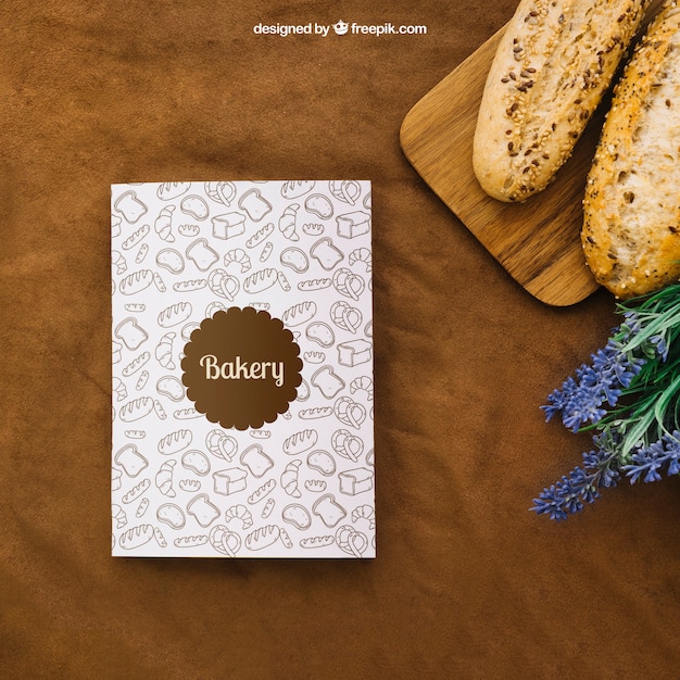 Free PSD book cover mockup with bread and flowers
