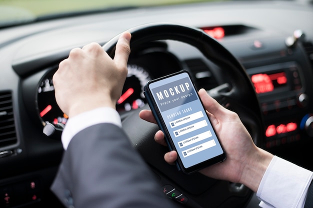Businessman holding smartphone while driving