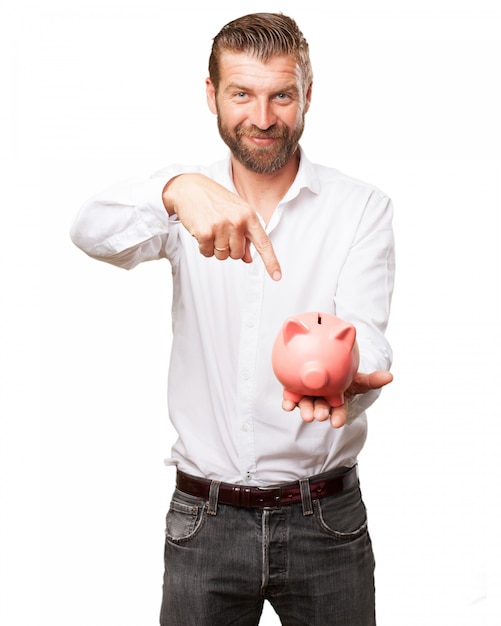 Cheerful man pointing at his piggy bank