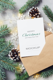 콘과 화환이 있는 봉투와 전나무가 있는 크리스마스 인사말 카드 모형