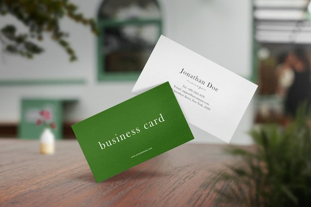 Clean minimal business card mockup on cafe background with vase tree branches and plant foreground