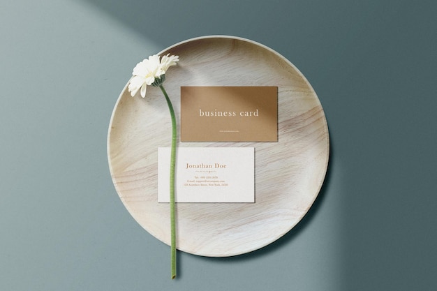 Чистый минимальный макет визитки на деревянной тарелке с цветком