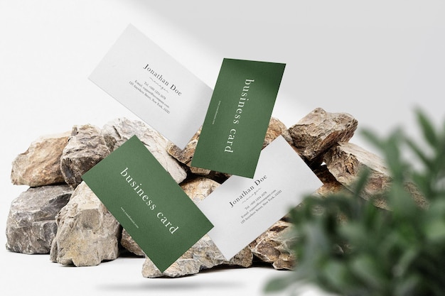 Clean minimal business cards mockup floating on stones with plant background. psd file.