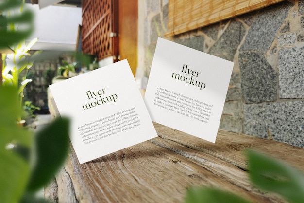 Clean minimal square flyer mockup floating on wood bench with leaves. psd file.