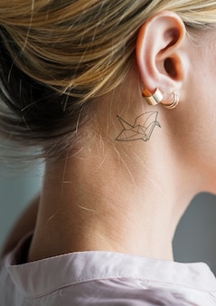 Closeup of a simple behind the ear tattoo of a young woman