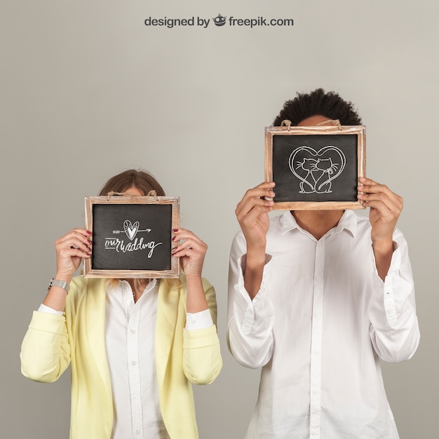 Couple holding slates in front of face