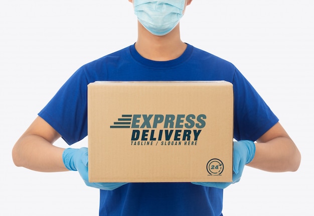 Delivery man hand in medical gloves and wearing mask holding cardboard box mockup