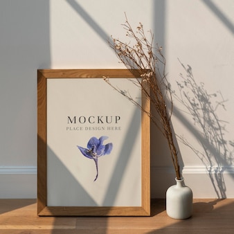 Dried white statice flower in a white vase by a wooden frame  mockup on a wooden floor