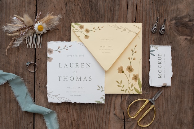 葉​と​花​と​紙​の​モックアップ​素朴な​結婚式​の​招待状​の​フラット​レイ