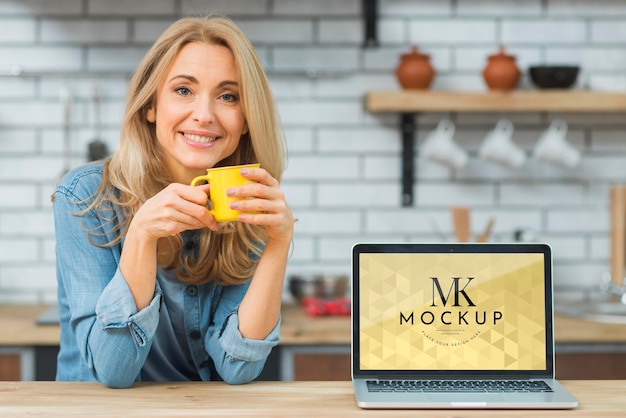 Front view of woman in the kitchen with coffee and laptop