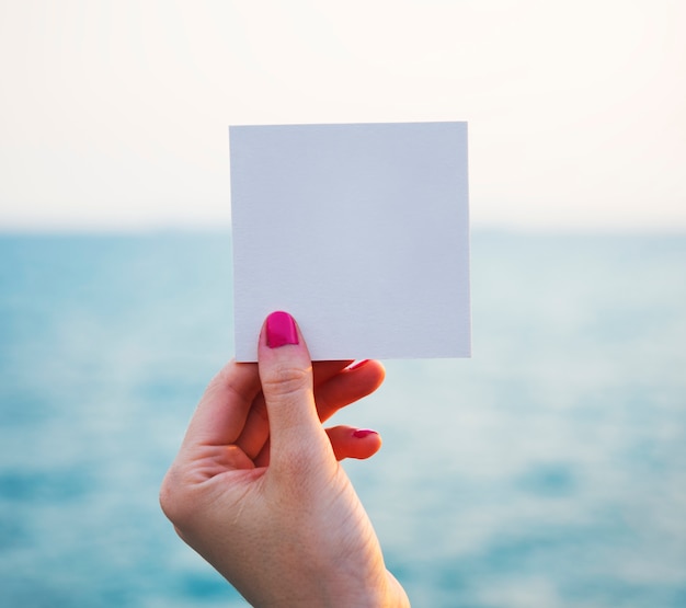 Hand holding perforated paper frame with ocean background