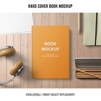 Free PSD hard cover book mockup with headphones and pencils
