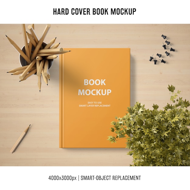 Free PSD hard cover book mockup with plant and pencils
