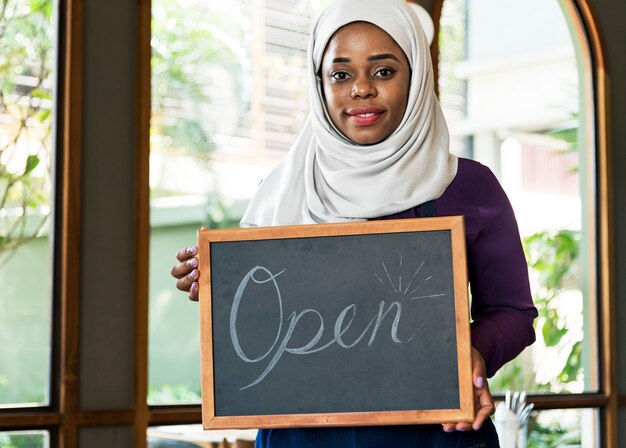 Islamic woman small business owner holding blackboard with smiling