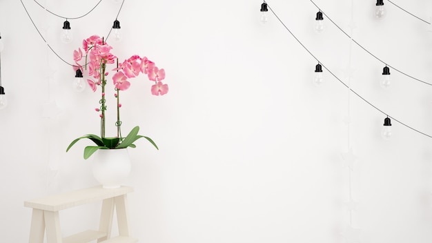 白い壁と美しい装飾的なピンクの花に掛かっているランプ