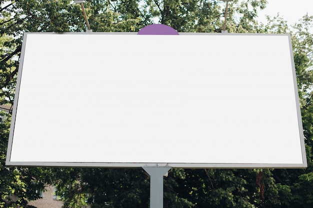 Большой рекламный щит с рекламным изображением на нем в парке на улице
