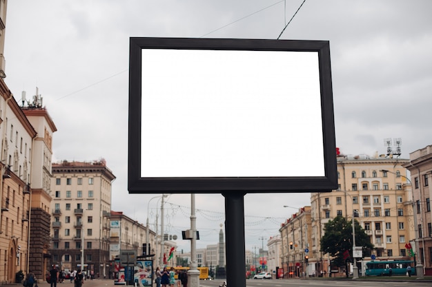 A large billboard with interesting information and advertising on it installed along a wide street in the city center