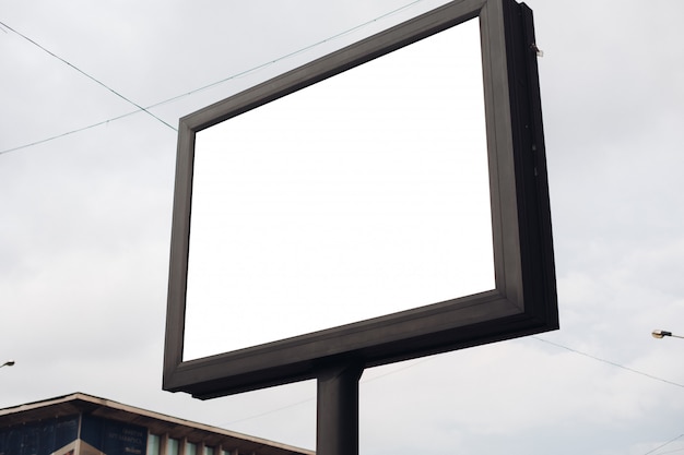 A large billboard with interesting information and advertising on it installed along a wide street in the city center