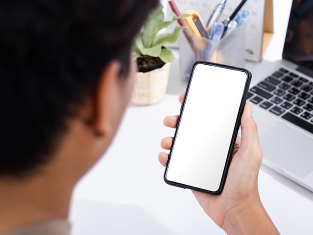 Man using a smartphone screen mockup at the white office desk