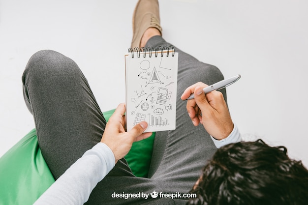 Free PSD mock up with relaxed man drawing on the notebook