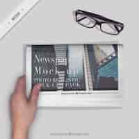 Free PSD person reading a newspaper with a glasses on the desktop