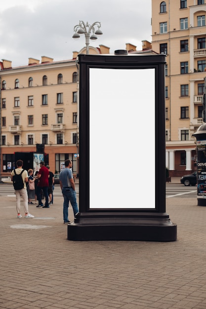 많은 사람들이 걷는 거리에 서있는 큰 광고판의 사진